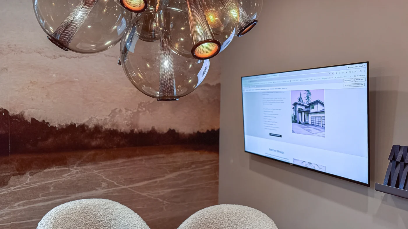 Close-up of the globular amber glass chandelier and a wall-mounted TV displaying an interior design website above a sherpa-style chair.